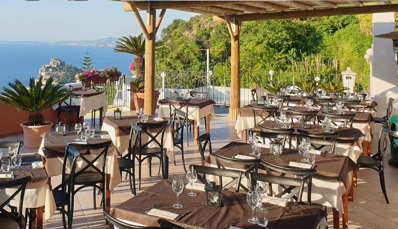 Tavolo apparecchiato sulla terrazza panoramica del Nascondiglio dell'Amore con il mare di Ischia sullo sfondo